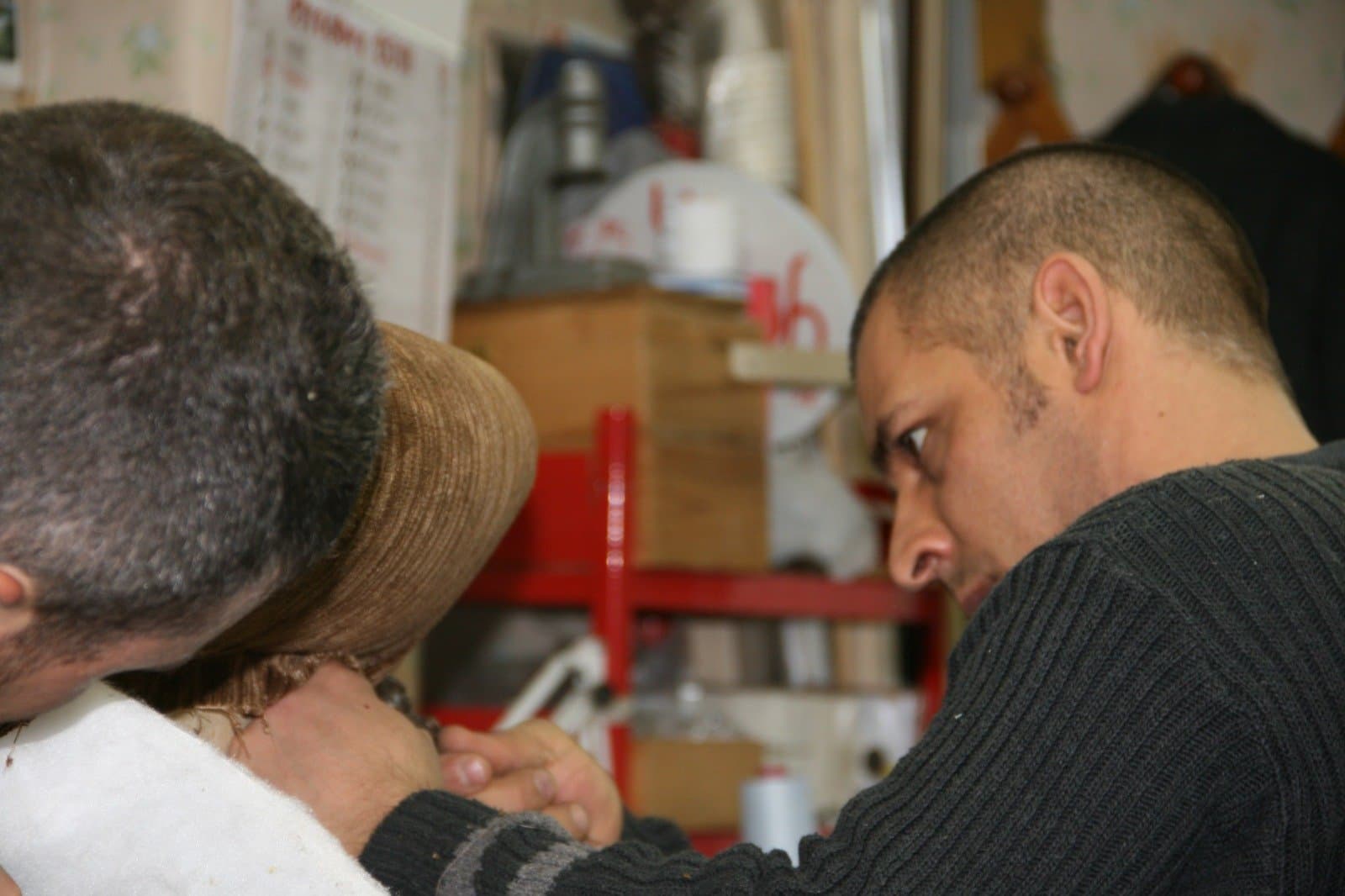 Due tappezzieri chini su una poltrona in lavorazione