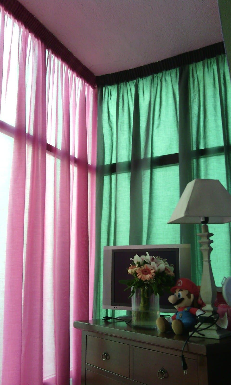 Coppia di tende rosa e verde su finestra ad angolo